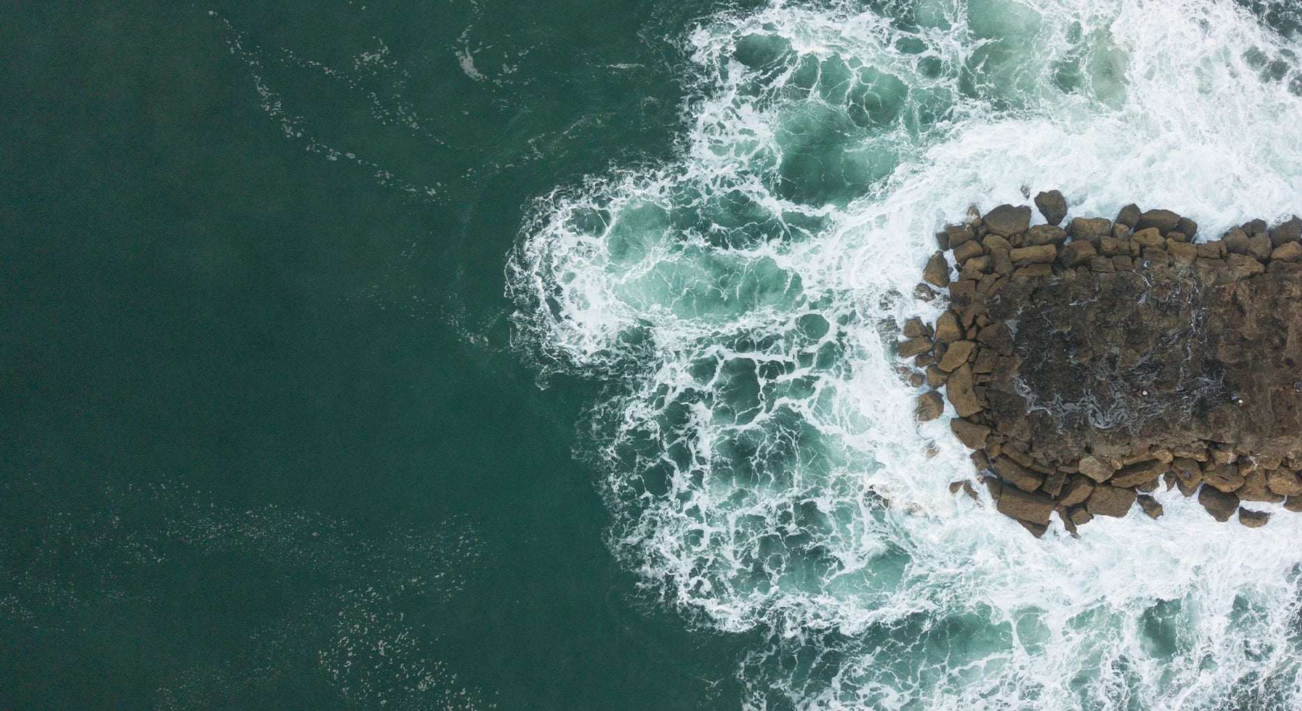 Aerial view of waves crashing against rocky coastline